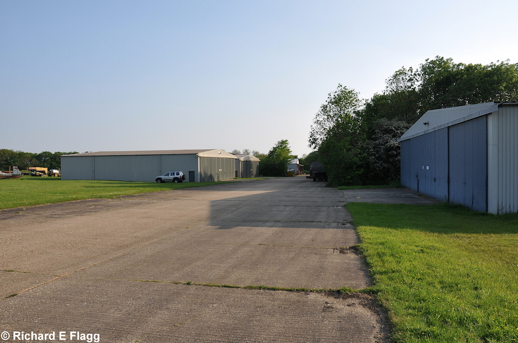 006Taxiway at the west of the airfield. Looking south west at one of the old dispersals, now where the club hangars are - 18 May 2014.png